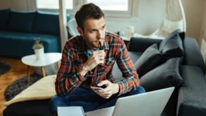 Man thinking at desk with laptop and notes, symbolizing preparation for Lake Lanier real estate 2025