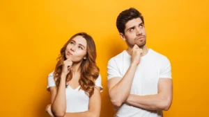 Thoughtful couple on a yellow backdrop symbolizing planning and expectations for housing in 2025